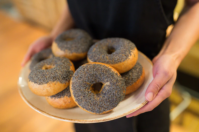 Person holding plate of poppy seed bagels