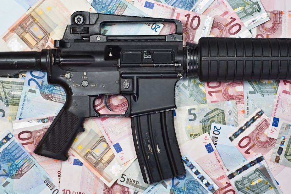 A machine gun lies over lots of Euro notes.
