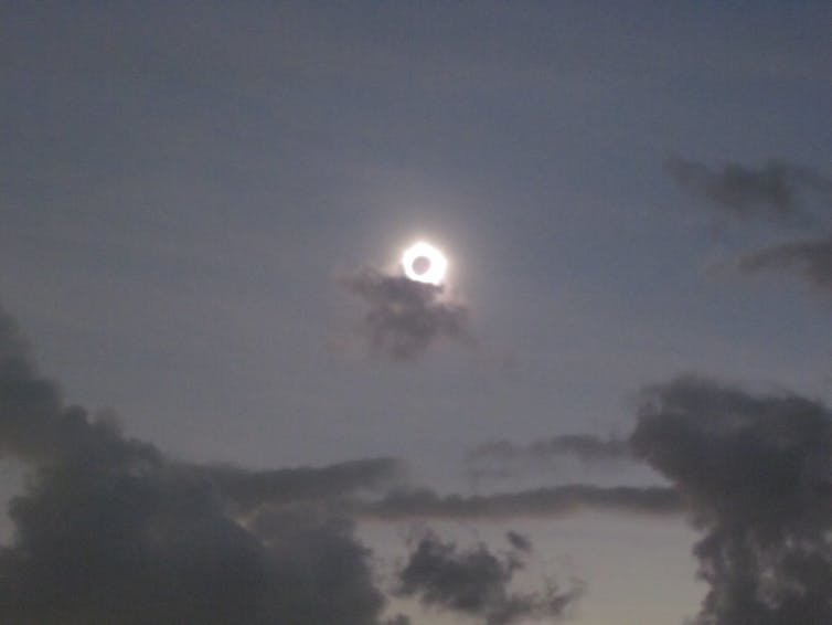 A small cloud covering an edge of the corona surrounding the dark disc of the eclipsed Sun