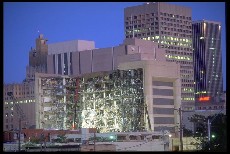 The facade of a partially destroyed, multi-story building on a city block.