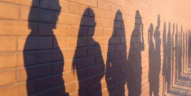 Shadows on wall showing people in a queue.