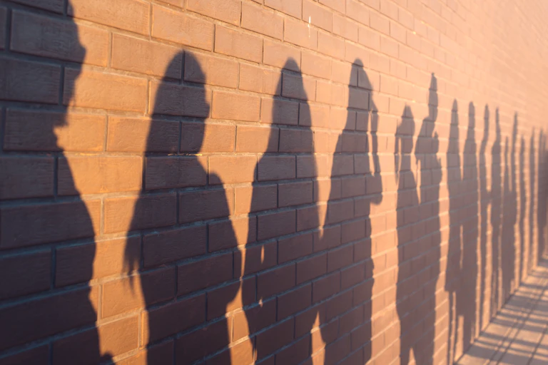Shadows on wall showing people in a queue.