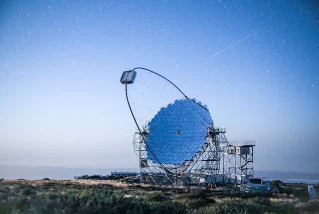 A round mirrored structure on a scaffolding with dark blue sky background