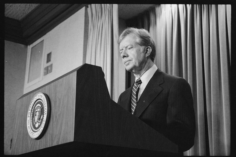A man in a suit standing behind a podium.