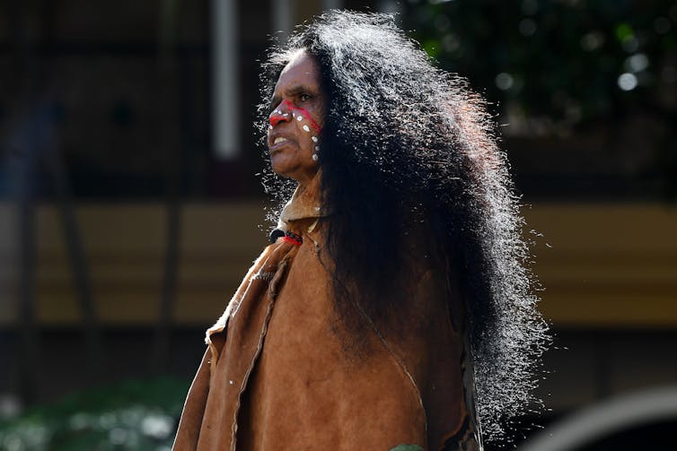 Indigenous woman wearing cloak and face paint