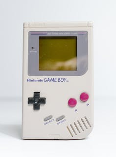 An original Game Boy console in grey with red buttons.
