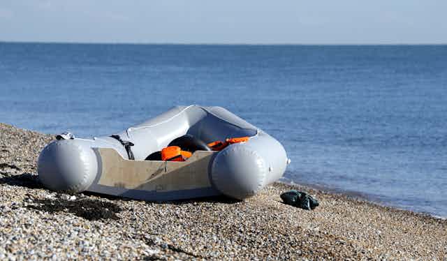 A rubber dinghy sitting empty on a stone beach in Kent, UK