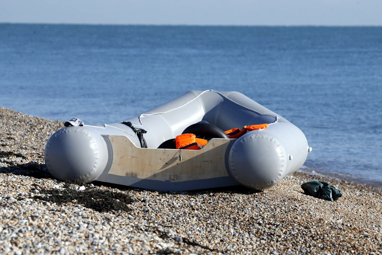 A rubber dinghy sitting empty on a stone beach in Kent, UK