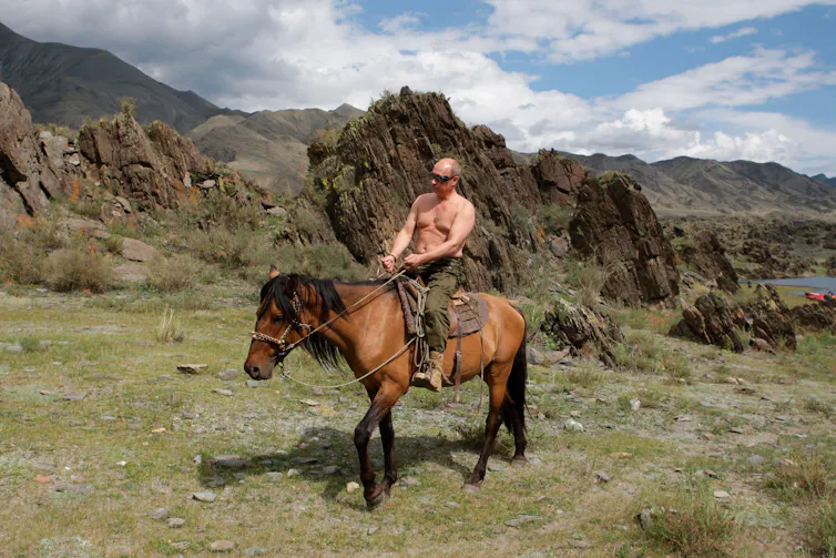 A topless Vladimir Putin riding horseback