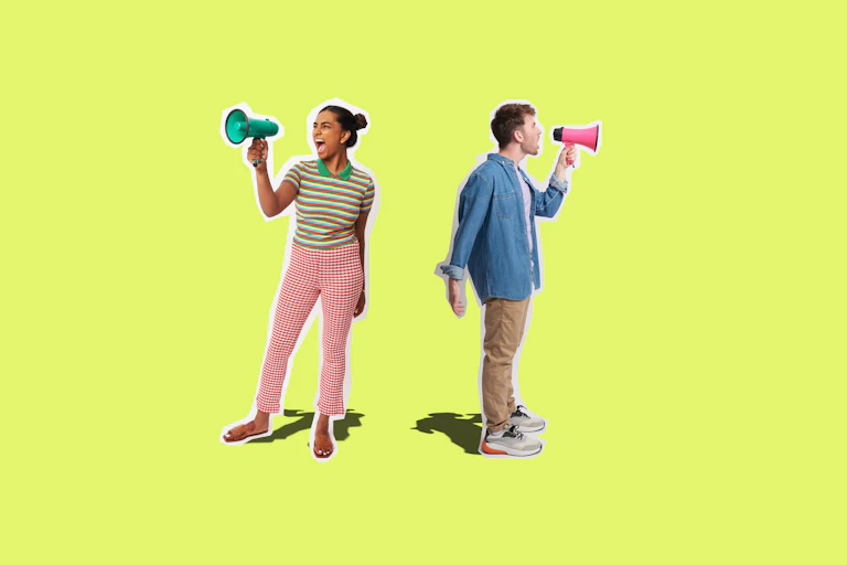 A woman in pink pants and a striped top yells into a megaphone as a man with a chambray shirt, his back to her, also yells in a different direction.