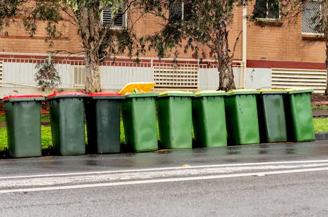 row of rubbish and recycling bins outside apartment building