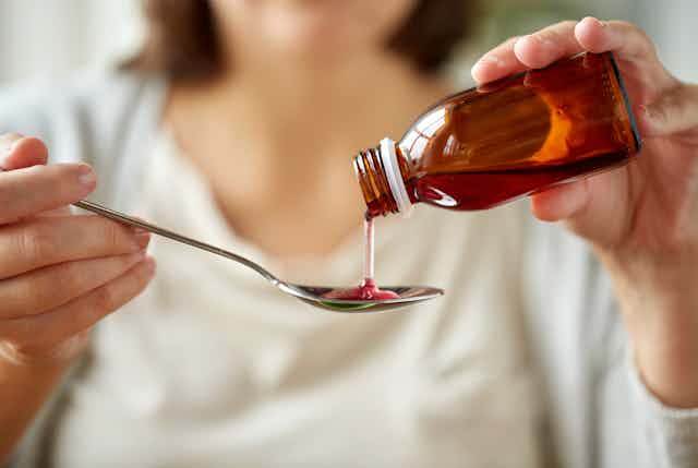 Woman pouring cough medicine onto tablespoon
