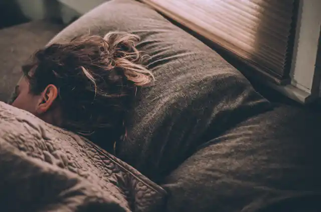 Woman sleeps in bed with light coming through