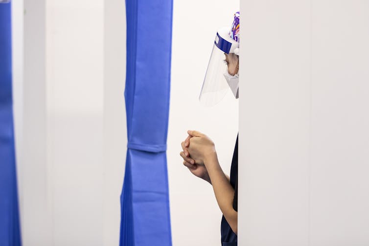 Profile of a nurse, wearing a face visor.