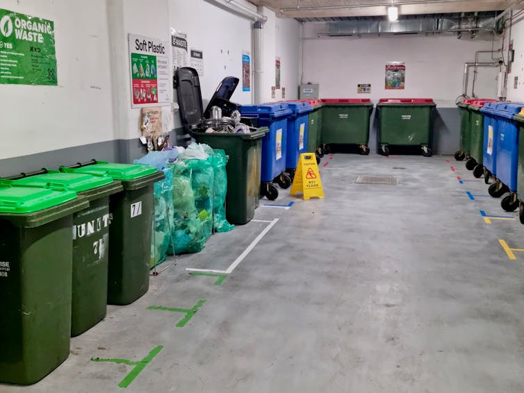 Bins for different kinds of waste lined up in the basement of an apartment complex