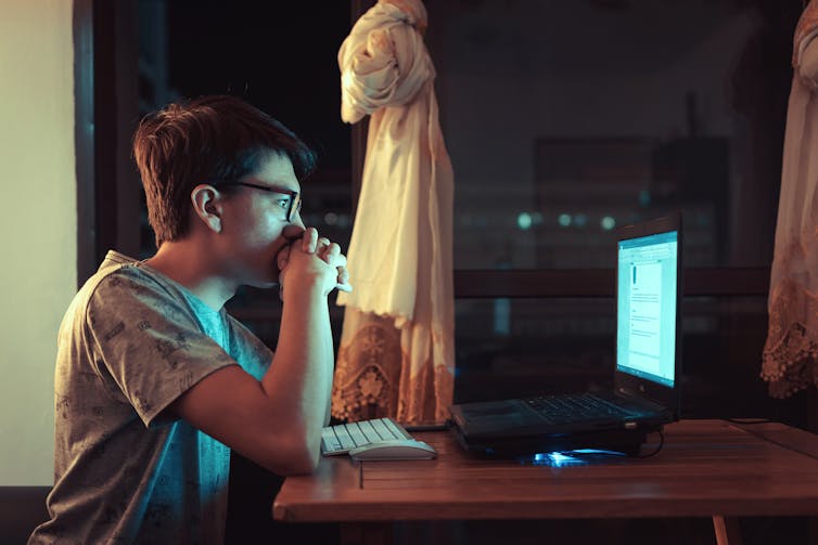 Man sits at a computer at night
