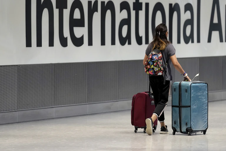 A young person seen walking with a bag at an airport.