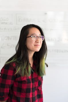 A young woman stands in front of a whiteboard.