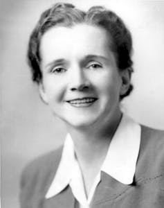 A black and white photo of a woman in a collared shirt, smiling.