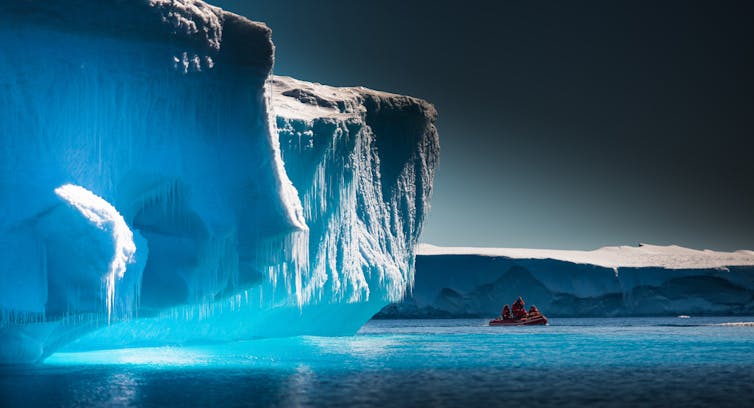 Científicos exploran icebergs antárticos en barco.