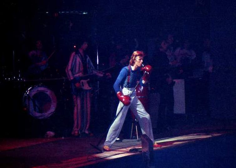 David Bowie on stage with red boxing gloves.