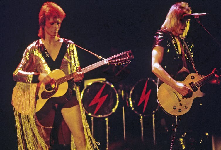 Two men with guitars on stage.