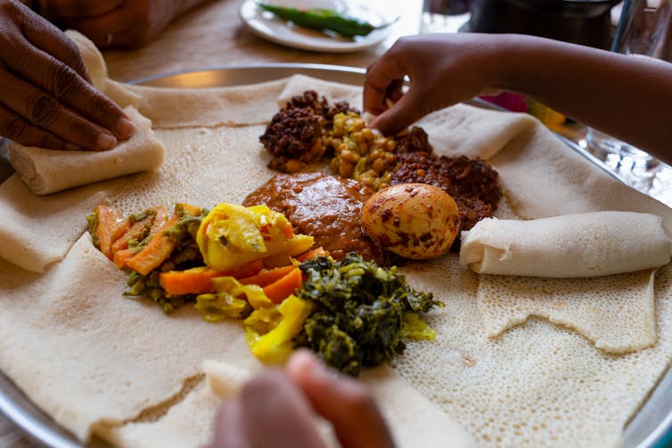 Grande galette de teff accompagnée de shiro, lentilles, œufs et légumes