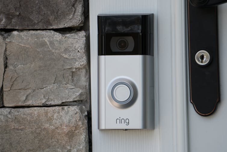 A black and silver ring doorbell on a door frame.