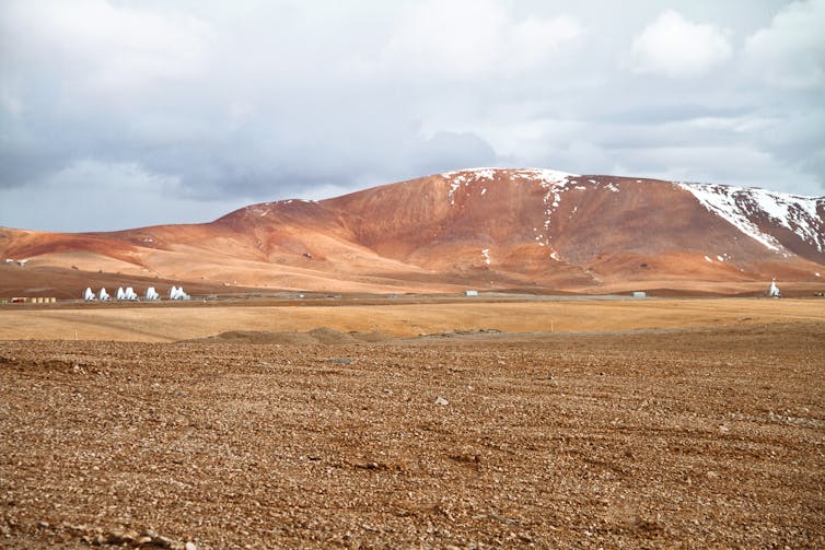 A number of satellite dishes in a remote desert.