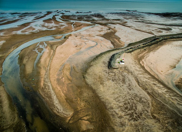 An aerial view of a sandy river delta with rivulets of water throughout