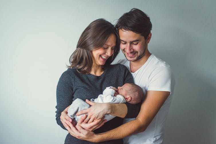 man and women look lovingly at baby