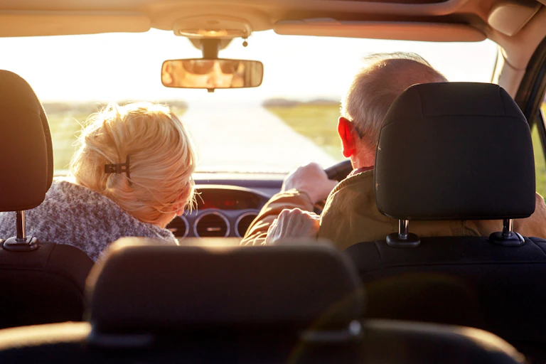 View from behind of elderly couple driving in a car