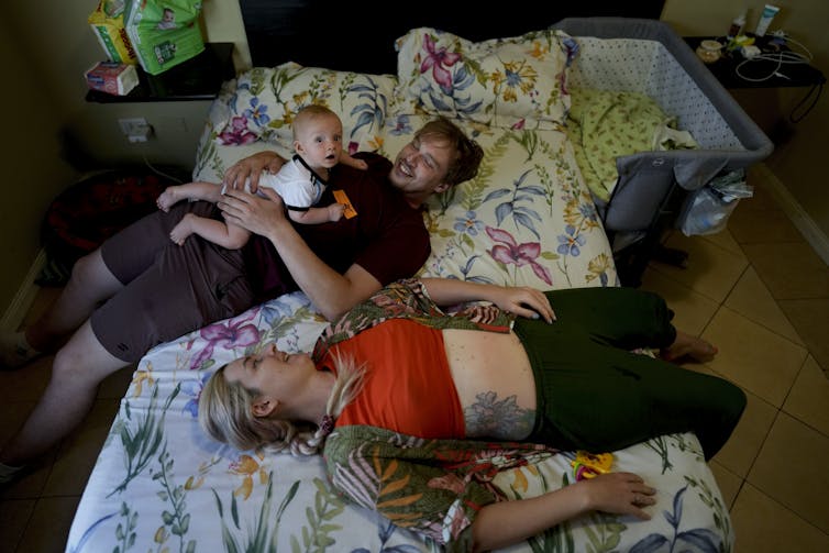 man and women lie on bed with baby
