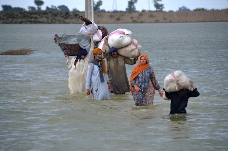 people wade through floodwaters
