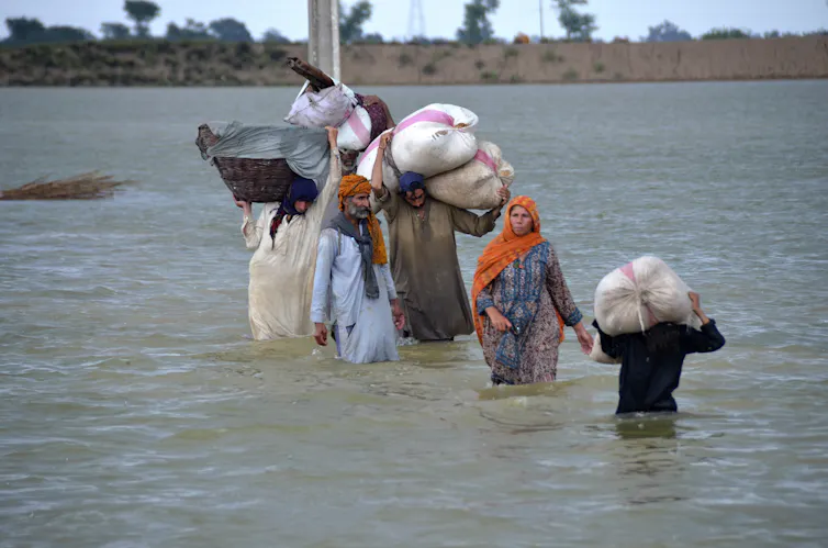 people wade through floodwaters