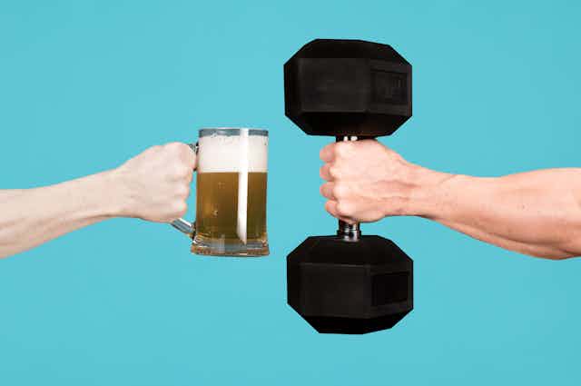 A hand holds a pint of beer. Another hand holds a large dumbbell.