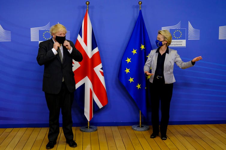Boris Johnson and Ursula von der Leyen wear face masks and stand a few feet apart, in front of UK and EU flags