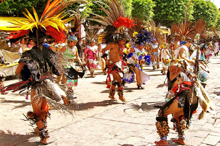 Bailarines con penachos danzan frente a frente en la calle.