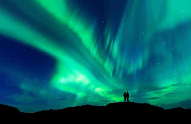 Aurora borealis with silhouette of hilltop