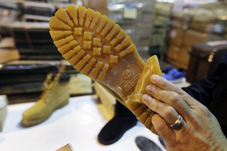 A hand peels down the tread on the sole of a boot to reveal a second tread beneath