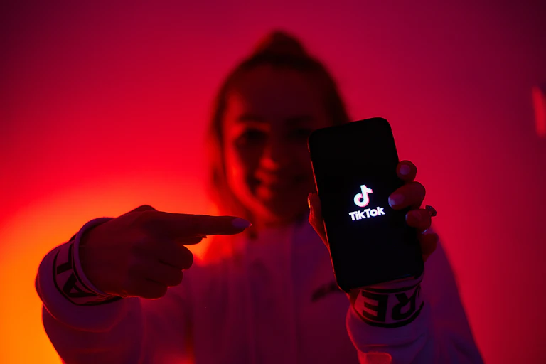 Jeune fille tenant un smartphone sur lequel s'affiche le logo de TiikTok