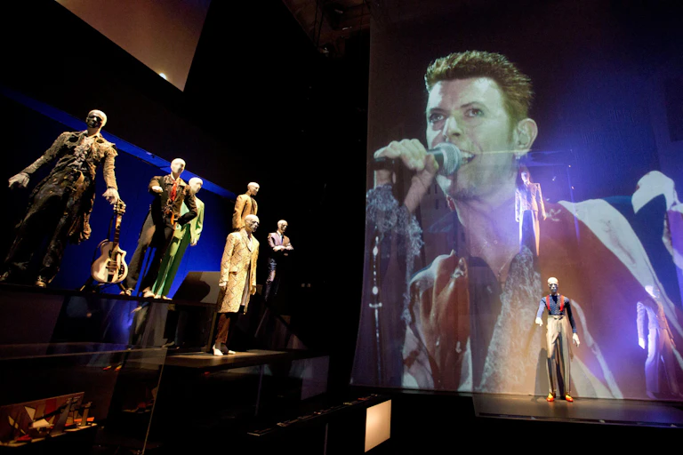 Mannequins and a projection in a dark exhibition space.