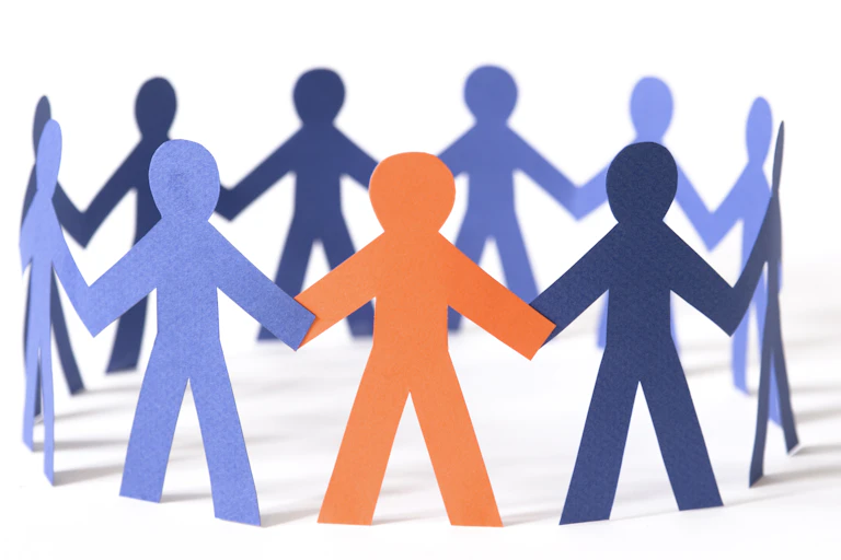 paper cutouts of people are pictured in a circle holding hands. most are blue, one is orange