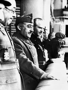 José Moscardó, Francisco Franco, Ramón Serrano Súñer miran por un balcón.
