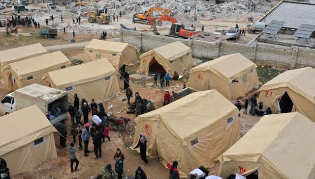 A dozen tents are set up near piles of rubble.