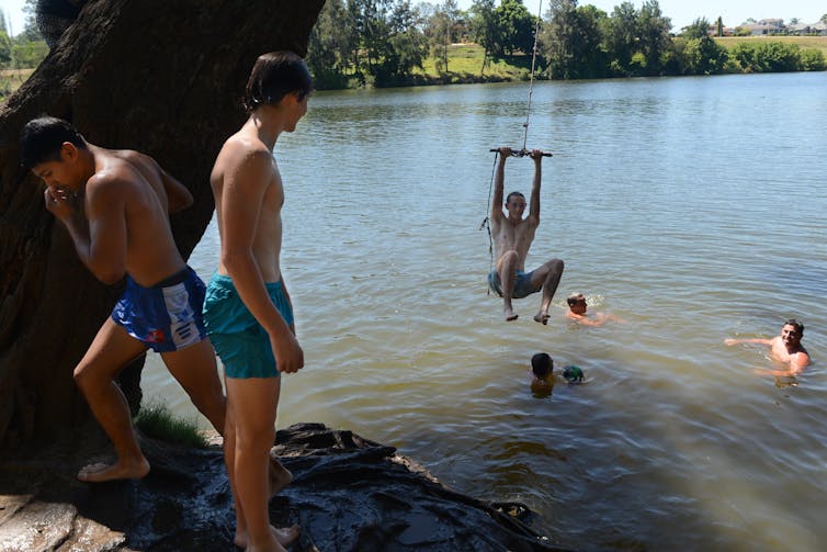 People swim and jump into a river