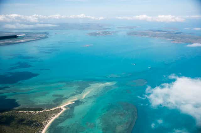 An aerial view of the Torres Strait Islands. The sea is bright blue, it's a sunny day and the islands are in view.