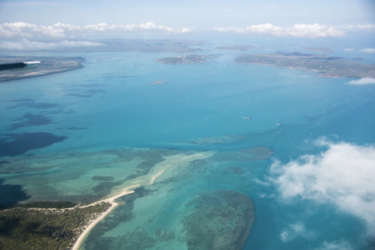 An aerial view of the Torres Strait Islands. The sea is bright blue, it's a sunny day and the islands are in view.