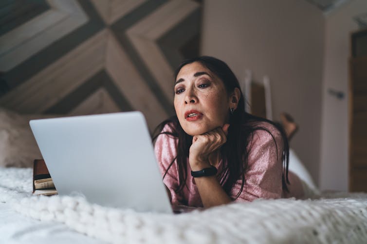 Woman looking at laptop in bed