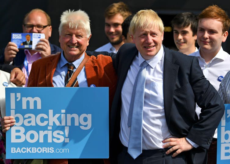 Stanley Johnson holding a sign reading 'I'm backing Boris' while standing next to his son, Boris Johnson.